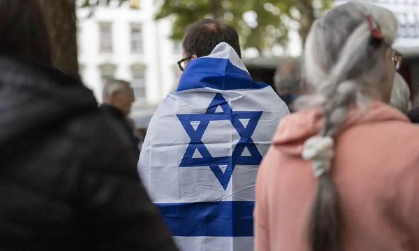 Un homme porte un drapeau israélien sur son dos à Zurich, le 7 octobre 2024, jour de commémoration de l'attaque du Hamas en Israël. KEYSTONE - TIL BUERGY