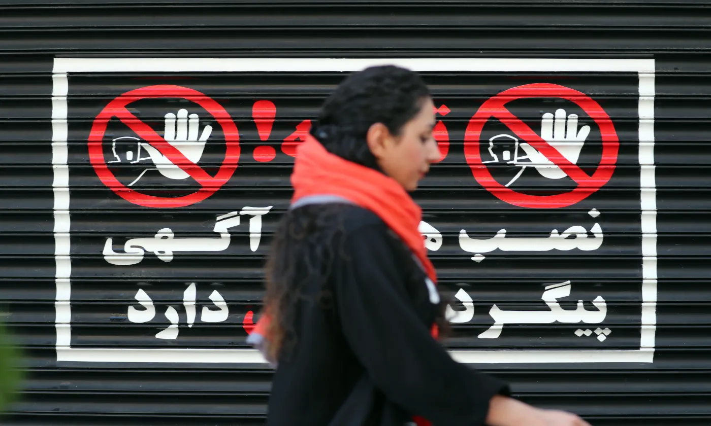 Le 10 août 2023. Une femme iranienne marche devant un magasin fermé de Téhéran, les cheveux au vent Keystone